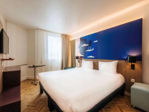 尼斯的住宿－尼斯機場宜必思尚品酒店，酒店客房设有一张白色大床和蓝色的墙壁。