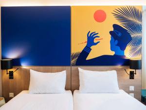 - 2 lits dans une chambre d'hôtel ornée d'une peinture murale dans l'établissement ibis Styles Nice Aéroport Arenas, à Nice