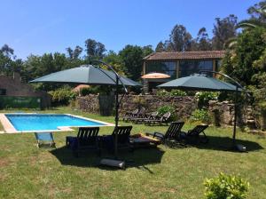 a group of chairs and umbrellas next to a pool at Casa Da Urcela in Ponteareas