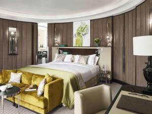 - une chambre avec un grand lit et un canapé jaune dans l'établissement Sofitel Frankfurt Opera, à Francfort-sur-le-Main