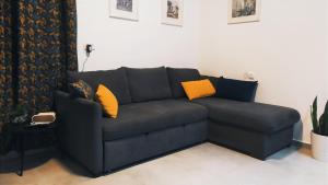 ein schwarzes Sofa mit orangefarbenen Kissen im Wohnzimmer in der Unterkunft On the sea in Aschkelon + 18 Fotos