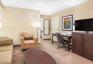 Habitación de hotel con escritorio, sillas y TV. en Baymont by Wyndham Red Deer, en Red Deer