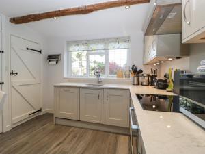 eine Küche mit weißen Schränken und einem Waschbecken in der Unterkunft Snowdrop Cottage in Sherborne
