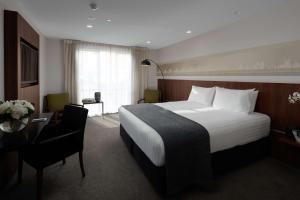 a hotel room with a large bed and a desk at Rydges Latimer Christchurch in Christchurch
