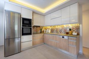 a kitchen with white cabinets and a stainless steel refrigerator at Southern Paradise Villas in Kalamaki