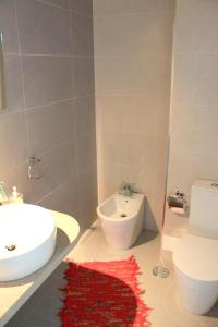 a bathroom with a sink and a toilet and a red rug at 2 bedrooms house with terrace at Nazare 1 km away from the beach in Nazaré
