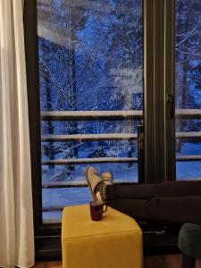 a coffee cup sitting on a yellow ottoman in front of a window at Apartman Djurdja in Divčibare