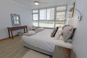 1 dormitorio con cama, escritorio y ventana en Ocean-Song, en Strand