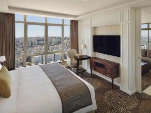 a hotel room with a large bed and a large window at M&ouml;venpick Hotel Amman in Amman