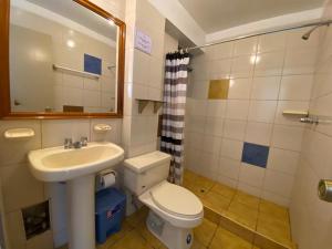 bagno con lavandino, servizi igienici e specchio di Hostal Oscar Inn a Puno