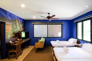 um quarto azul com 2 camas e uma secretária em Rain Tree Residence Hotel em Phayayen