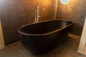 a black bath tub in a bathroom with a light at Agriturismo Terra del Sole in Albosaggia
