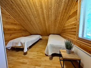 two beds in a room with a wooden ceiling at Jukuvilla in Kalajoki