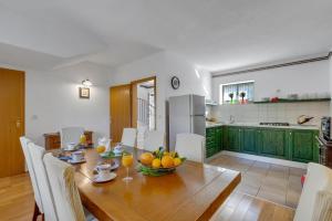 a kitchen and dining room with a wooden table with fruit on it at Villa Marta in Tucepi, private pool in Tučepi