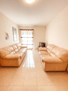 2 divani in pelle marrone in un soggiorno con finestra di Stresa Court Apartments a San Giuliano