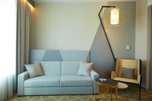 a living room with a blue couch and a table at Mercure Saransk Center in Saransk