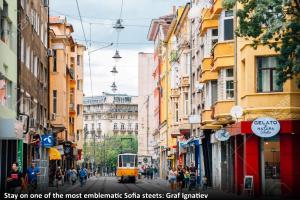 eine Straßenbahn auf einer Stadtstraße mit Gebäuden in der Unterkunft Top Center Semi-detached Apartment Studio in Sofia