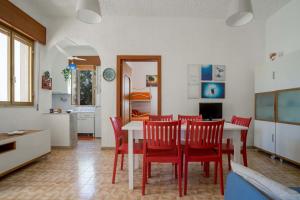 a dining room with a table and red chairs at Villa Margherita by BarbarHouse in Punta Prosciutto