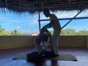 a man helping a woman in a yoga pose at Tattwamasi Ayuryoga with Breakfast and Yoga in Varkala