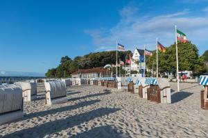 a row of beach chairs on a sandy beach with flags at Ferienwohnung Pape in Glücksburg
