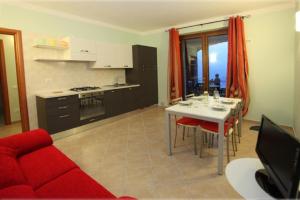 een keuken en een woonkamer met een rode bank en een tafel bij La Casa Di Pericle in Brenzone sul Garda