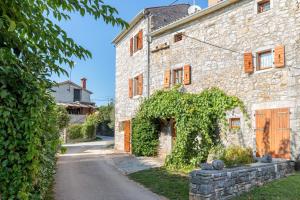 una vecchia casa in pietra con l'edera sul ciglio di una strada di Holiday Home Tamaris with Pool a Višnjan (Visignano)