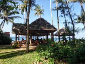 a restaurant on the beach with palm trees at Sukriti beach Resort in Varkala