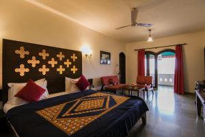 1 dormitorio con 1 cama con manta azul y almohadas rojas en Heritage Khirasara Palace, en Rajkot