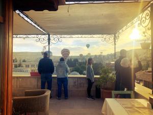 a group of people standing on a balcony looking at hot air balloons at Walnut House in Goreme