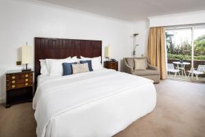 a bedroom with a large white bed and a chair at The Atlantic Hotel - Small Luxury Hotels of the World in St Brelade