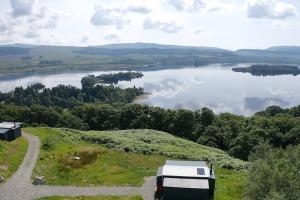 a rv parked on a hill next to a lake at Odhrán Lodge, St Conan's Escape: Home with a view in Loch Awe
