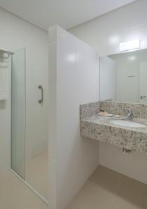 a bathroom with a shower and a sink and a mirror at Hotel Glória in Blumenau