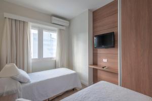a hotel room with two beds and a television at Hotel Glória in Blumenau