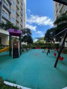 um parque infantil vazio com escorrega e baloiços em Cozy 1 BR Apartment At South Residences Tower 2 em Manila