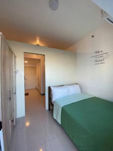 a bedroom with a green bed and a hallway at Cozy 1 BR Apartment At South Residences Tower 2 in Manila