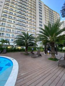 a large building with palm trees and a swimming pool at Cozy 1 BR Apartment At South Residences Tower 2 in Manila