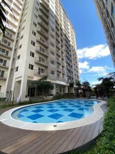 a swimming pool in front of a large building at Cozy 1 BR Apartment At South Residences Tower 2 in Manila