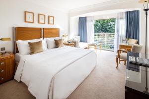 een slaapkamer met een groot wit bed en een bureau bij The Atlantic Hotel - Small Luxury Hotels of the World in St Brelade