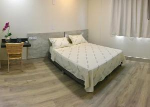um quarto com uma cama, uma secretária e uma mesa em Hotel Avalon Maringá Econômico em Maringá