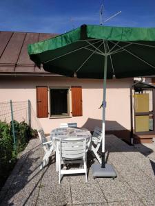 tavolo e sedie con ombrellone verde di One bedroom house with enclosed garden at Pontebba 8 km away from the slopes a Pontebba