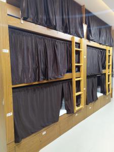 a row of bunk beds with black curtains at Super Dormitory AC DELUXE in Mumbai