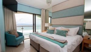 a bedroom with a large bed and a blue chair at 803 Bermudas - by Stay in Umhlanga in Durban