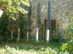 a fence with beads on it in front of a building at La Maison Du Ruisseau in Conilhac-Corbières