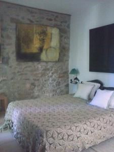 1 dormitorio con cama y pared de piedra en La Maison Du Ruisseau, en Conilhac-Corbières