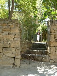 a woman standing on a fence next to a stone wall at La Maison Du Ruisseau in Conilhac-Corbières