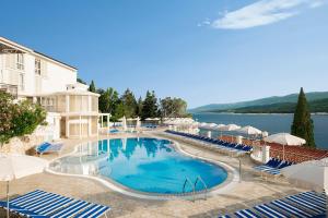 a swimming pool with chairs and umbrellas at a resort at Valamar Sanfior Hotel & Casa in Rabac