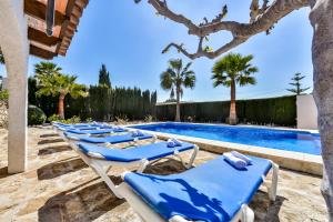 eine Reihe blauer Liegestühle neben einem Pool in der Unterkunft Villas Guzman - Flores in Benissa