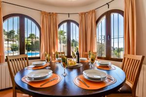 uma sala de jantar com mesa, cadeiras e janelas em Villas Guzman - Flores em Benissa