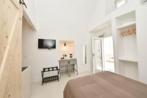 Habitación blanca con cama, mesa y TV. en CASA FLAMI' 3, en Ostuni