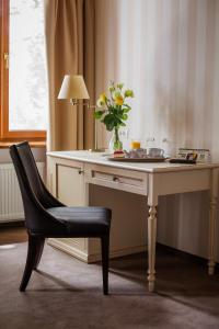 uma secretária com uma cadeira e um vaso com flores em Premier Geneva Hotel em Odessa